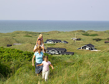 Familie på deres sommerhus- grund med udsigt til havet