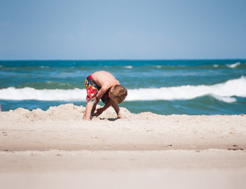 Lille dreng graver på stranden i Tornby