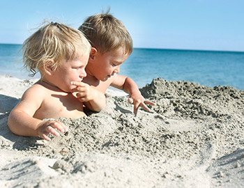 To børn leger i sandet ved stranden i Tversted